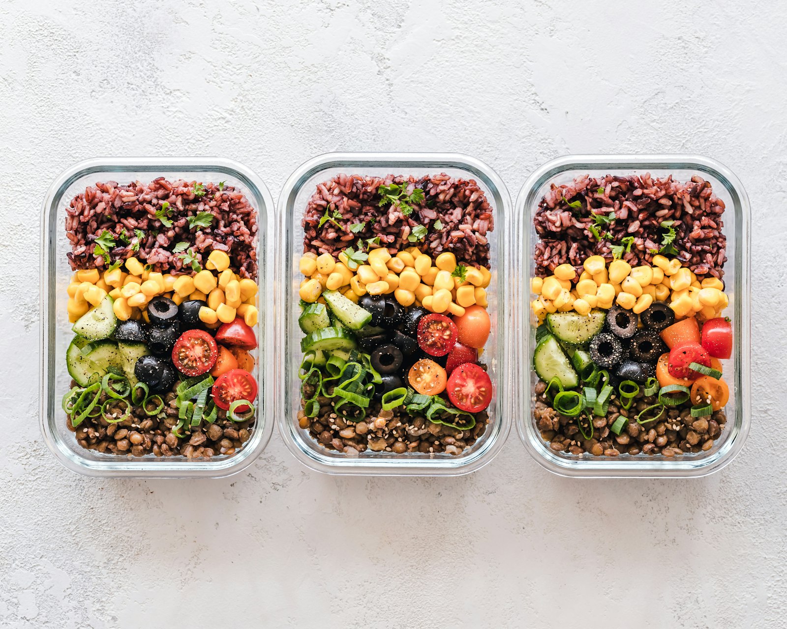 Portioned weekly meal prep containers with rice, vegetables, and lentils