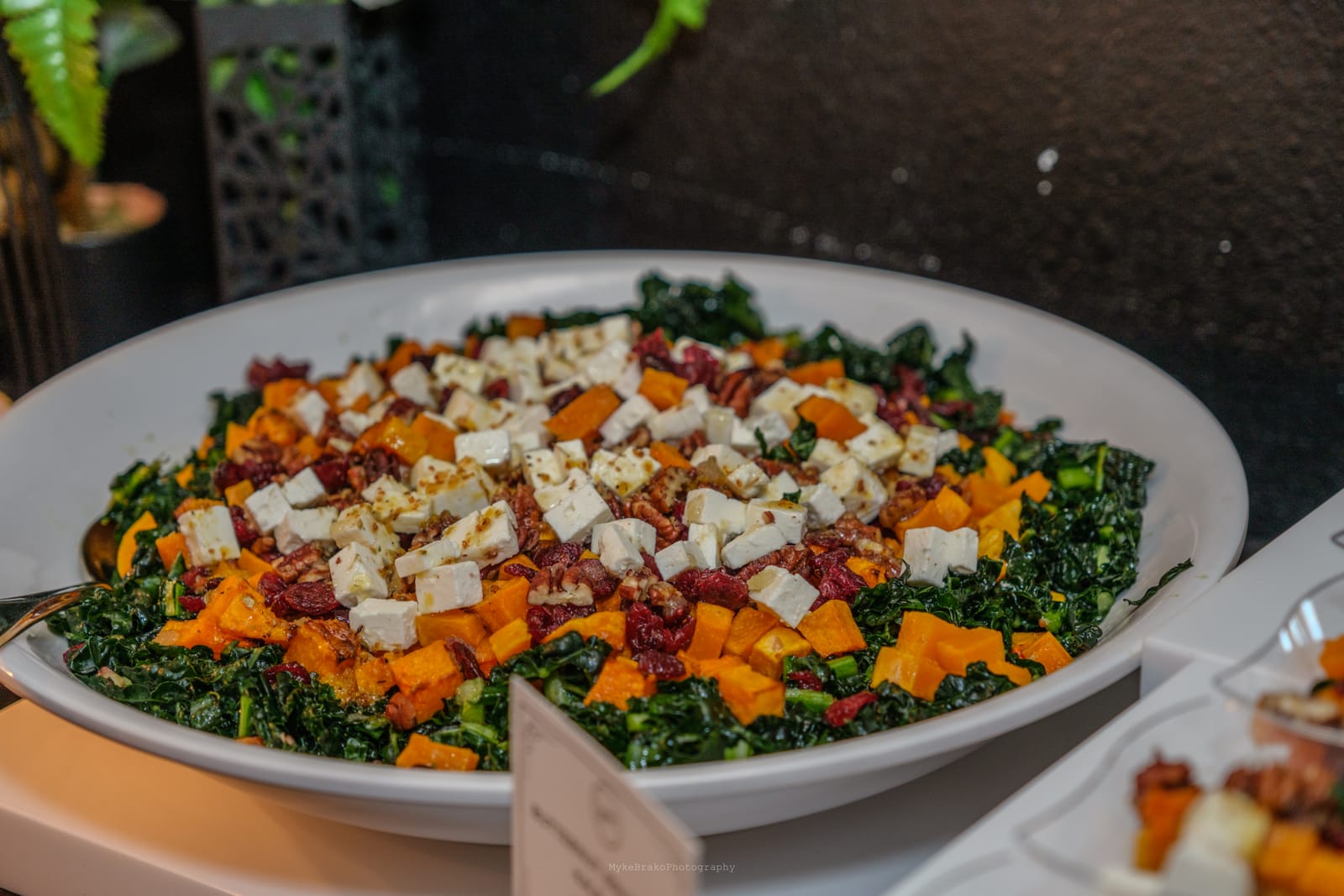 A large bowl of GourmetMaria's kale and butternut squash salad with feta and pecans